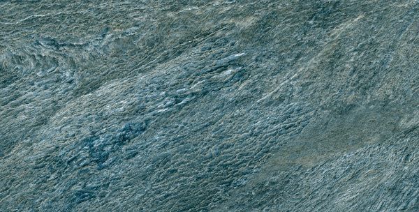 A close-up of the Amazonia 24x48 Glazed Porcelain Tile reveals rough textures and layered gray-blue patterns, resembling Brazilian Slate or weathered rock.