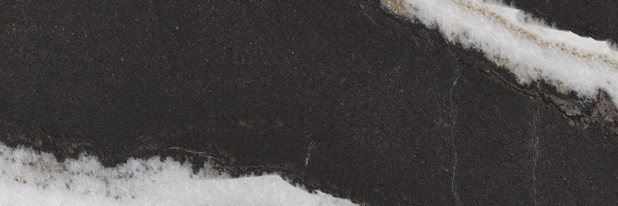 Close-up of a black stone surface with textured white and light gray veins running diagonally across, creating a striking natural pattern.