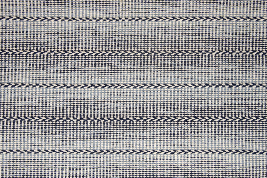 Orzola On Trend Carpet features horizontal rows of dark blue chevrons separated by tightly woven gray and white threads, creating a textured geometric pattern perfect for contemporary and modern interiors.