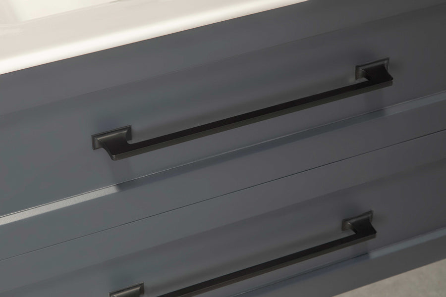 Close-up of two dark metal handles on gray drawers, with a white countertop visible at the top of the image. The handles have a rectangular, modern design.