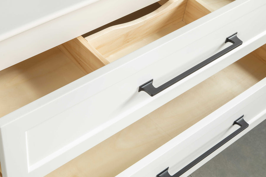 A close-up view of two open white wooden drawers with black handles, revealing empty, light-colored interiors and a built-in wooden divider in the top drawer.