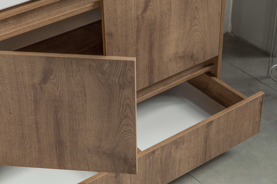 A close-up view of a wooden cabinet with two drawers partially open, revealing empty white interiors. The cabinet stands on a gray tiled floor.