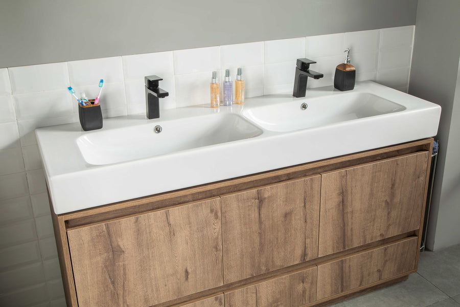 Double sink vanity with a white countertop, wood cabinets, two black faucets, and accessories including toothbrush holders, soap dispenser, and bottles against a tiled backsplash.