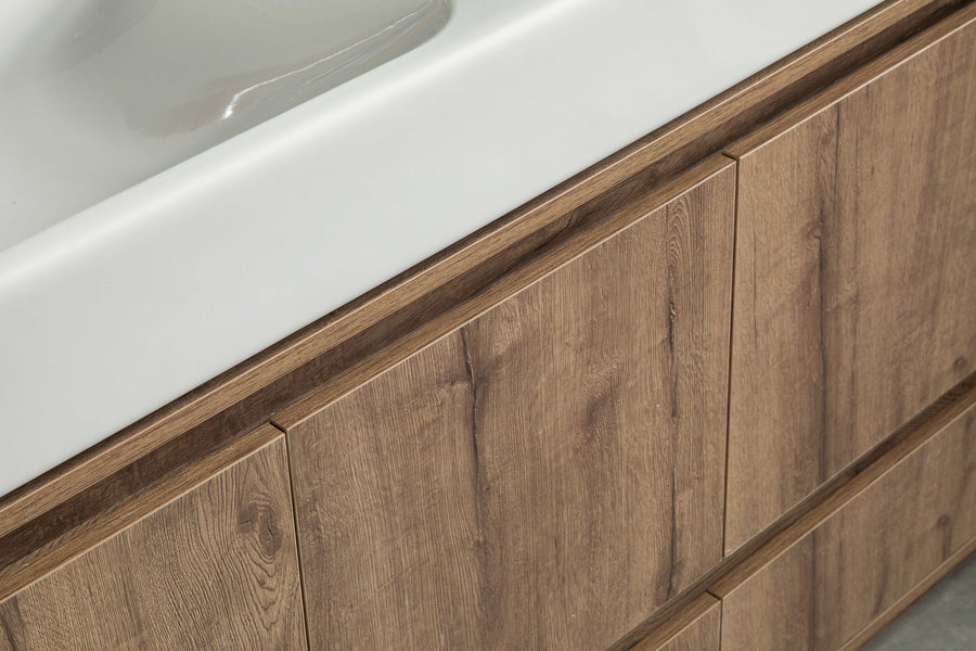 Close-up of a bathroom vanity with a white sink on top and wood-textured cabinet doors below, featuring a natural brown finish and modern, minimalist design.