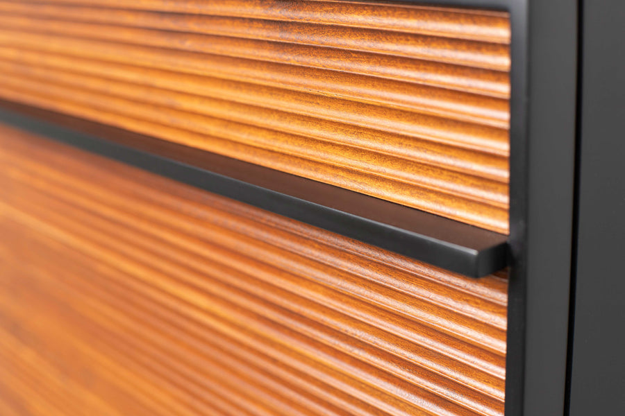 Close-up of a modern cabinet with horizontal ridged wooden panels and a sleek black metal handle. The wood has a warm, natural finish and the design appears contemporary and minimalistic.