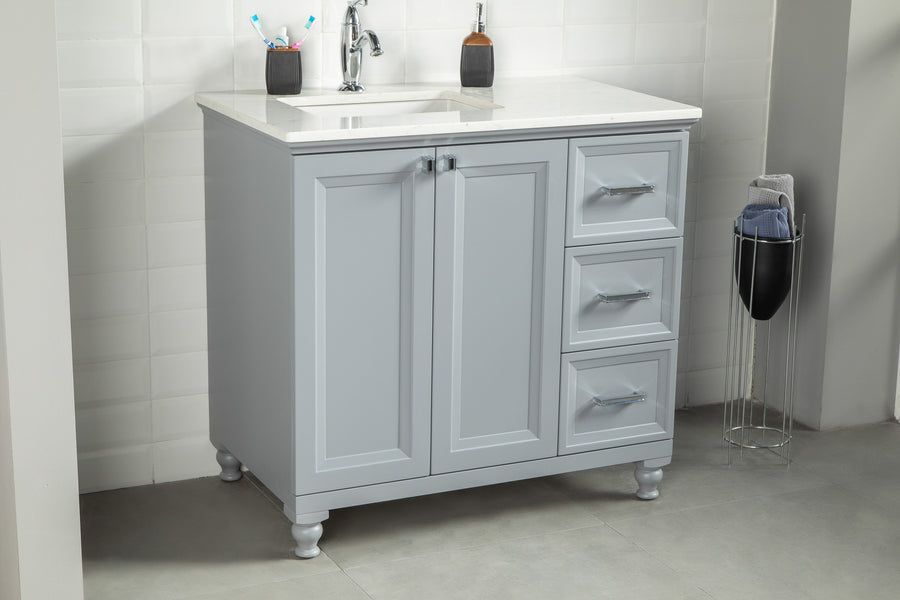 A light gray bathroom vanity with a white countertop, sink, and chrome faucet, standing on tile flooring. Three drawers and two cabinet doors are visible. A soap dispenser and two toothbrush holders sit on the counter.