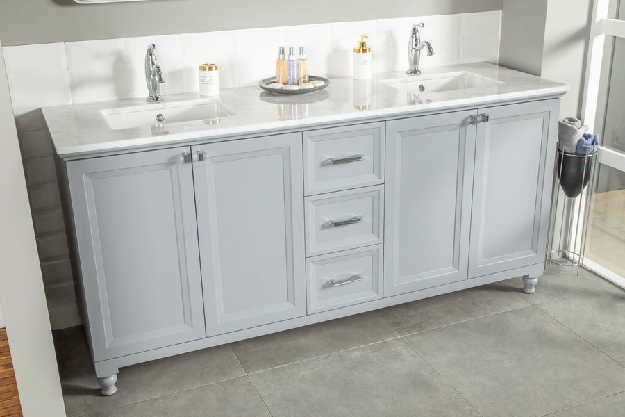 A modern bathroom vanity with a light gray finish, double sinks, chrome faucets, a marble countertop, and three central drawers. Toiletries and soap dispensers are on the counter, with a towel hanging on the right.