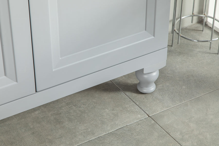Close-up of the lower corner of a gray cabinet with decorative round leg, standing on light gray tiled floor near a metal stool.