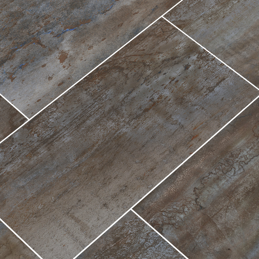 Oxide 12x24 Rectified Ceramic Tile features a textured, weathered surface in brown, gray, and blue tones. Its rectangular shape and offset pattern with white grout make it ideal for backsplashes or countertops.