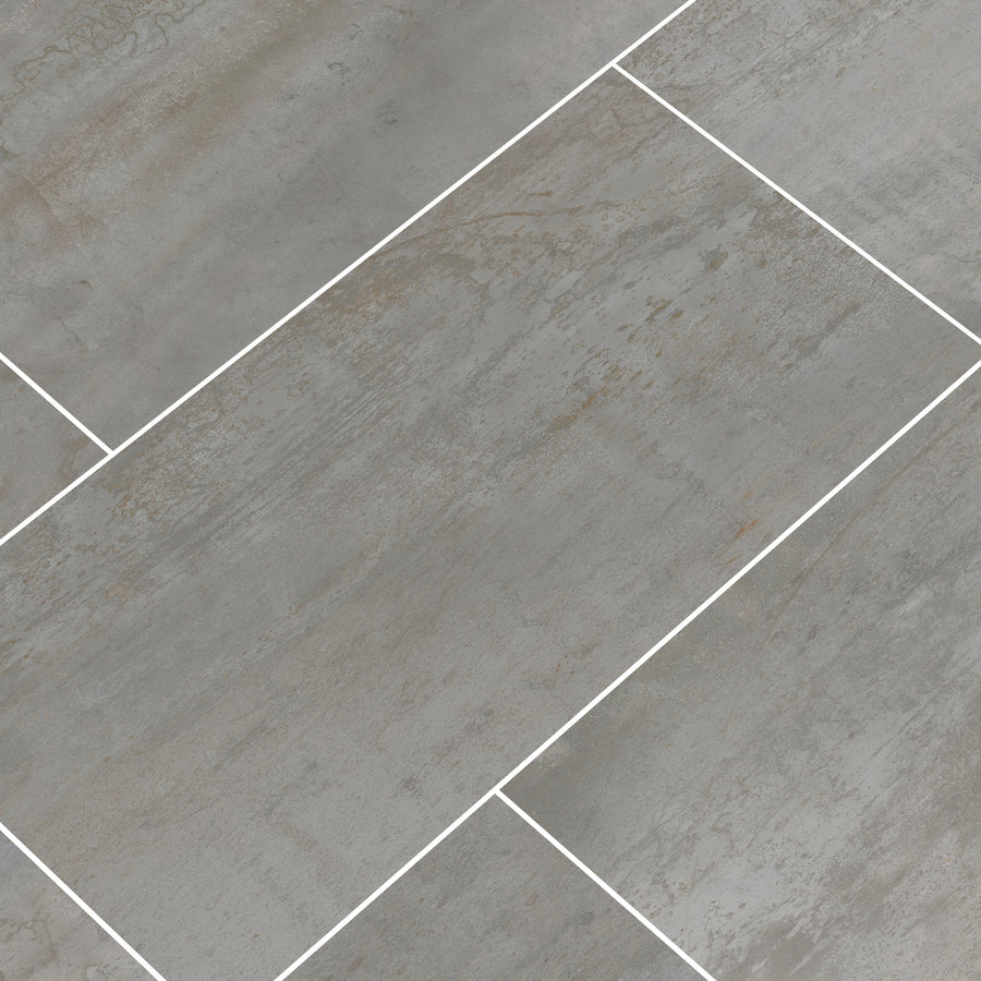 Oxide 12x24 Rectified Ceramic Tiles feature a gray hue with subtle texture and slight color variation, arranged in an offset pattern with white grout—perfect for floors, countertops, and backsplashes.