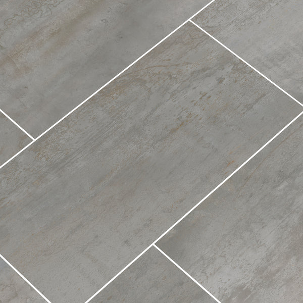 Oxide 12x24 Rectified Ceramic Tiles feature a gray hue with subtle texture and slight color variation, arranged in an offset pattern with white grout—perfect for floors, countertops, and backsplashes.