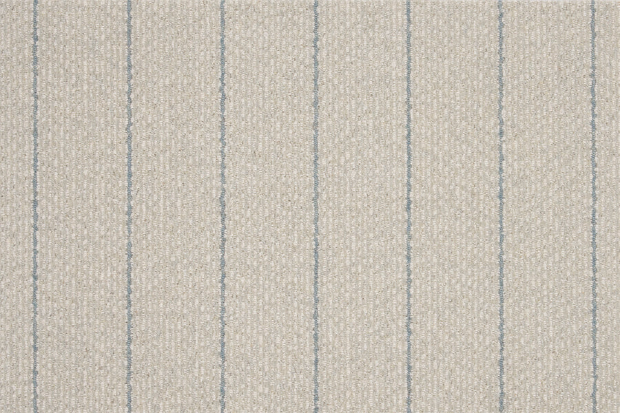 Featuring a textured beige surface with evenly spaced thin vertical blue lines, Pacific Stripe On Trend Carpet in Mist delivers a simple yet contemporary striped pattern.
