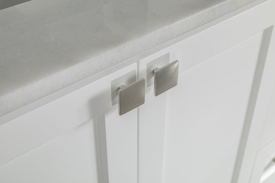 Close-up of white cabinet doors with square silver handles, topped with a smooth, light gray countertop.