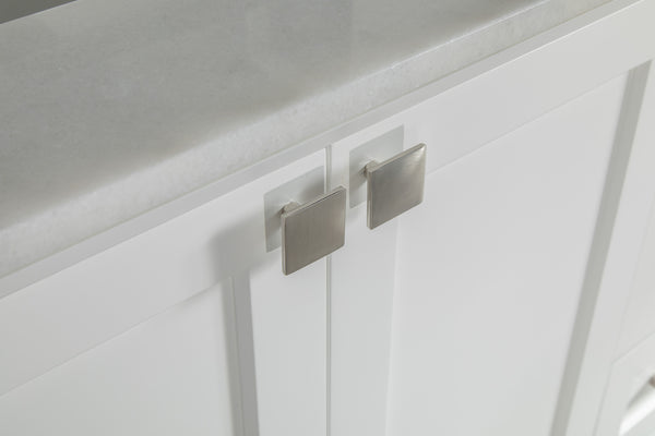 Close-up of white cabinet doors with square silver handles, topped with a smooth, light gray countertop.