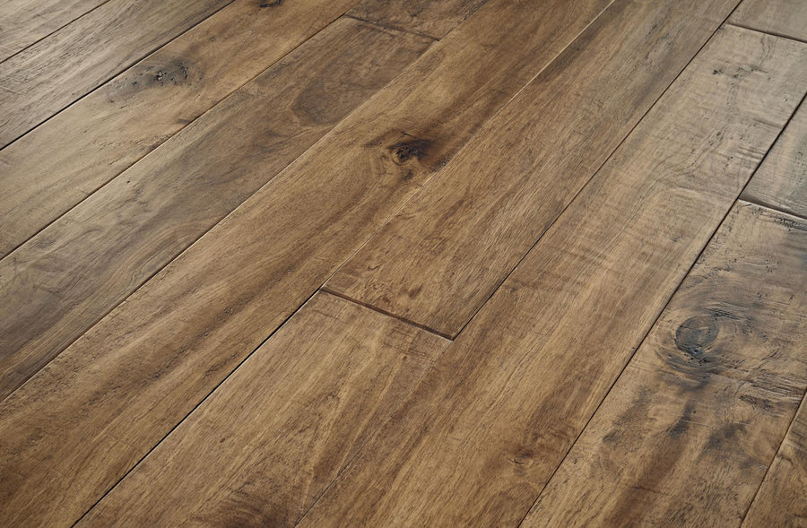 Close-up view of wooden floorboards with a natural, warm brown finish, visible wood grain, and knots, arranged in a staggered pattern.