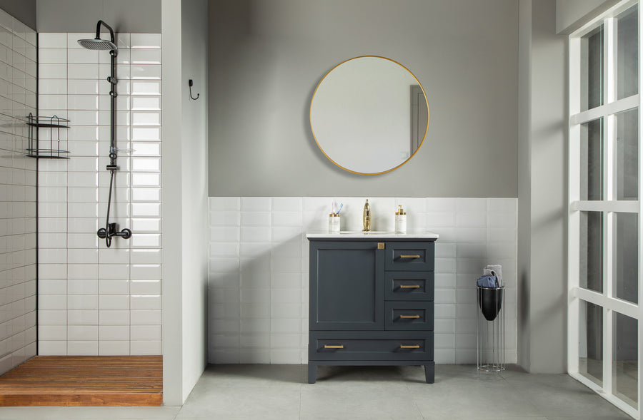 Modern bathroom with a walk-in shower, white tiles, wooden floor, light gray walls, and large window. Features a Paloma 30" Vanity with soft close drawers and toiletries, round mirror above, and tall trash can to the right.