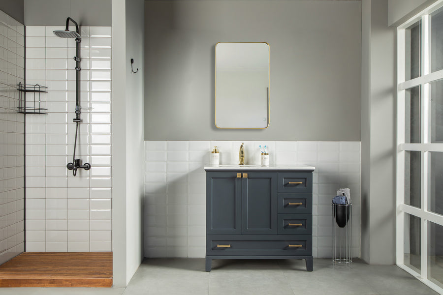 Modern bathroom with a walk-in shower featuring white subway tiles and a rainfall showerhead. The Paloma 36" Vanity with soft close drawers is at the center, complemented by a gold mirror in this clean, minimalist space.