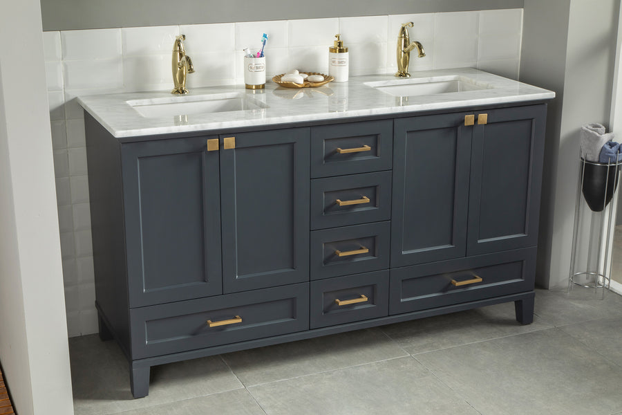 Double-sink bathroom vanity with dark blue cabinets, gold hardware, white marble countertop, and gold faucets, set against a white tile backsplash and sitting on gray floor tiles.