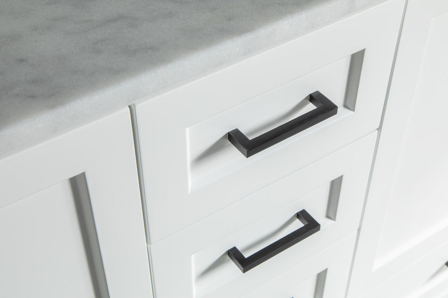 Close-up of white kitchen drawers with modern black rectangular handles and a light gray marble countertop. The design is clean and minimalistic.
