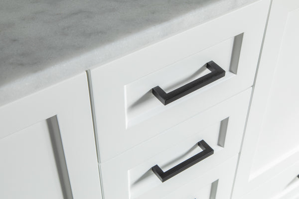Close-up of white kitchen drawers with modern black rectangular handles and a light gray marble countertop. The design is clean and minimalistic.