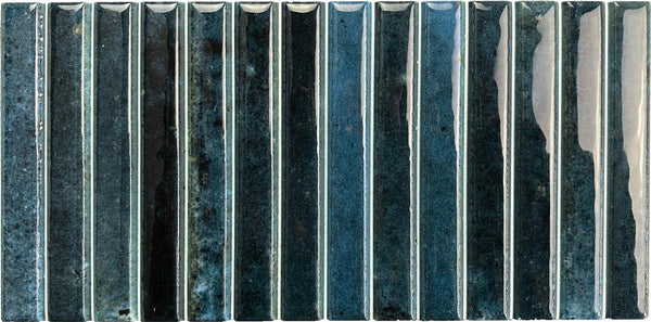 Parallel 4.5 x 9.1 Glazed Porcelain Tiles in blue and black feature a fluted, glossy finish. Arranged vertically, their subtly uneven surfaces create a textured and reflective look.