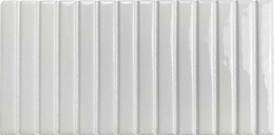 The Parallel 4.5 x 9.1 Glazed Porcelain Tile is a rectangular, white tile with a glossy finish and vertical, evenly spaced raised ridges that create a bold fluted design for added texture and visual depth.