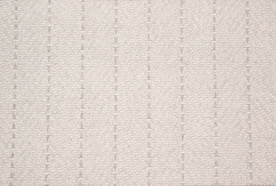 Close-up of Angola Berber Carpet in Parchment—a beige fabric with a textured woven pattern and subtle vertical dotted lines. The soft, minimalist, neutral design makes it ideal for contemporary interiors.