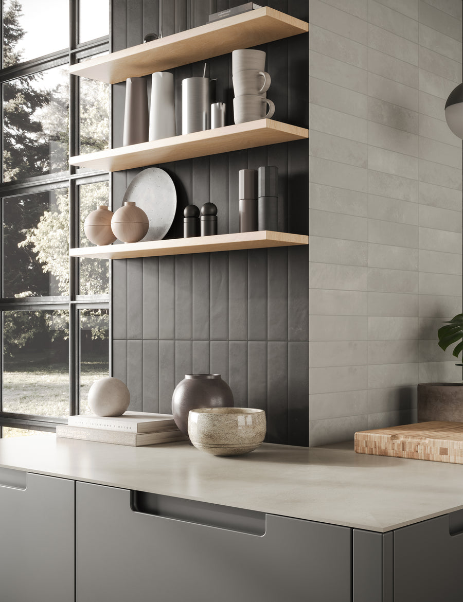 Modern kitchen with light countertops, dark cabinets, and a tiled backsplash. Wooden shelves hold ceramic vases, bowls, and dishes. Large windows let in natural light, revealing a view of trees outside.