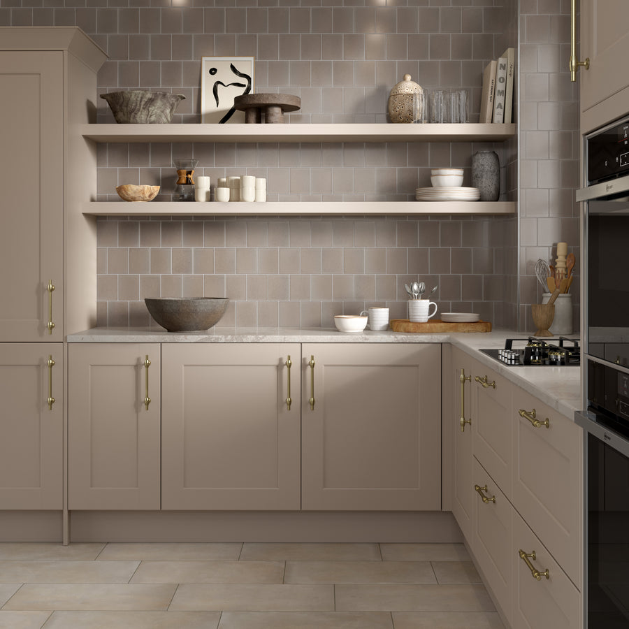 A modern kitchen with beige cabinets, brass handles, open wooden shelves displaying dishes and decor, a tiled backsplash, and a gas stovetop on a light countertop.