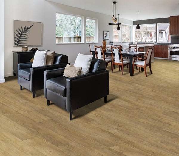 Open-plan living and dining area with light wood flooring, two black armchairs with neutral cushions, a dining table set for eight, modern kitchen appliances, and large windows letting in natural light.