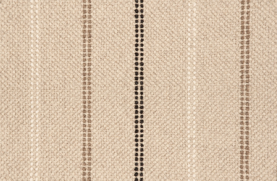 A close-up of Prairie Path On Trend Carpet shows its textured beige fabric with brown and black vertical stripes, featuring a woven pattern—an elegant design that brings sophisticated style to any space.