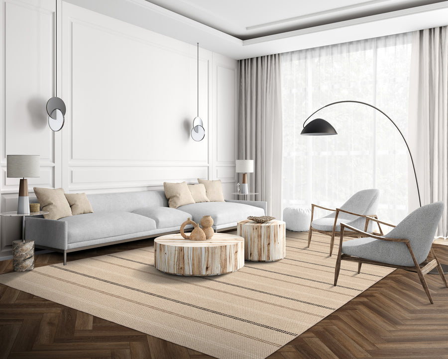 Modern living room with a gray sectional sofa, two gray armchairs, round wooden coffee tables, a large floor lamp, neutral decor, floor-to-ceiling curtains, and a striped area rug on wood flooring.