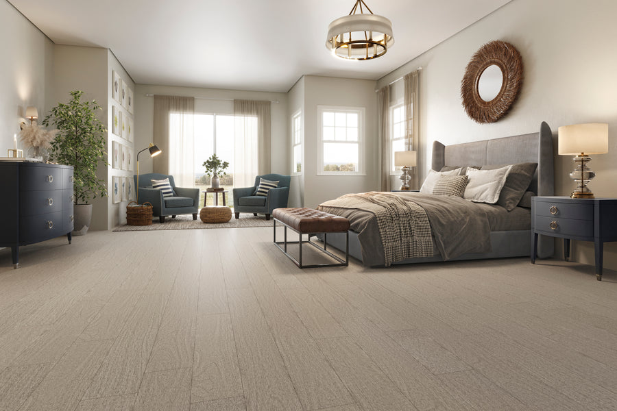 Spacious, modern bedroom with a large upholstered bed, neutral bedding, two nightstands with lamps, a cushioned bench, armchairs near bright windows, and decorative accents on walls and furniture.