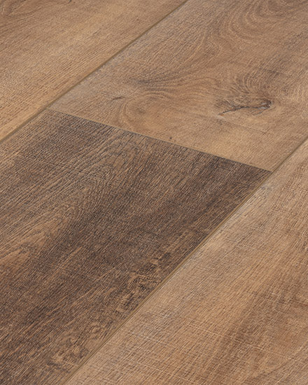 Close-up of Moda Living 7.15" Luxury Vinyl Plank flooring, highlighting the natural grain pattern, varied brown shades, and subtle texture differences between boards.