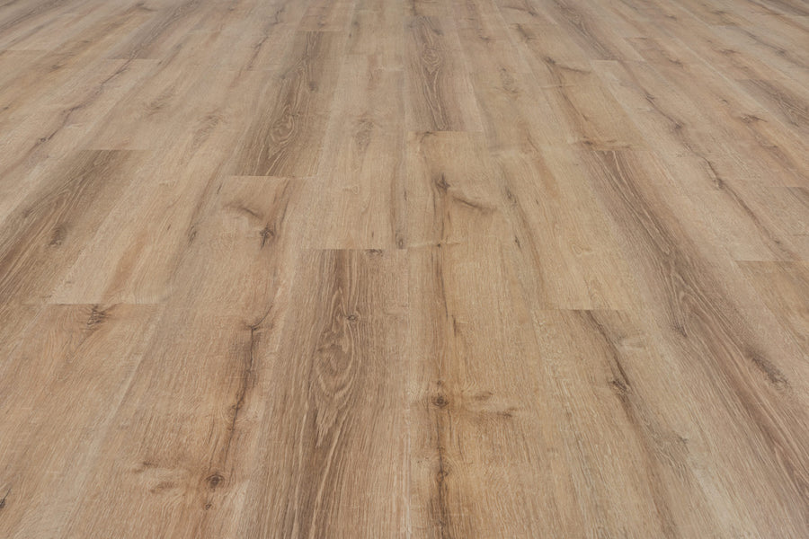 A close-up of Uptown Chic 7.15" Luxury Vinyl Plank flooring, featuring a light brown tone and natural grain pattern, extends into the distance to create a sense of depth.