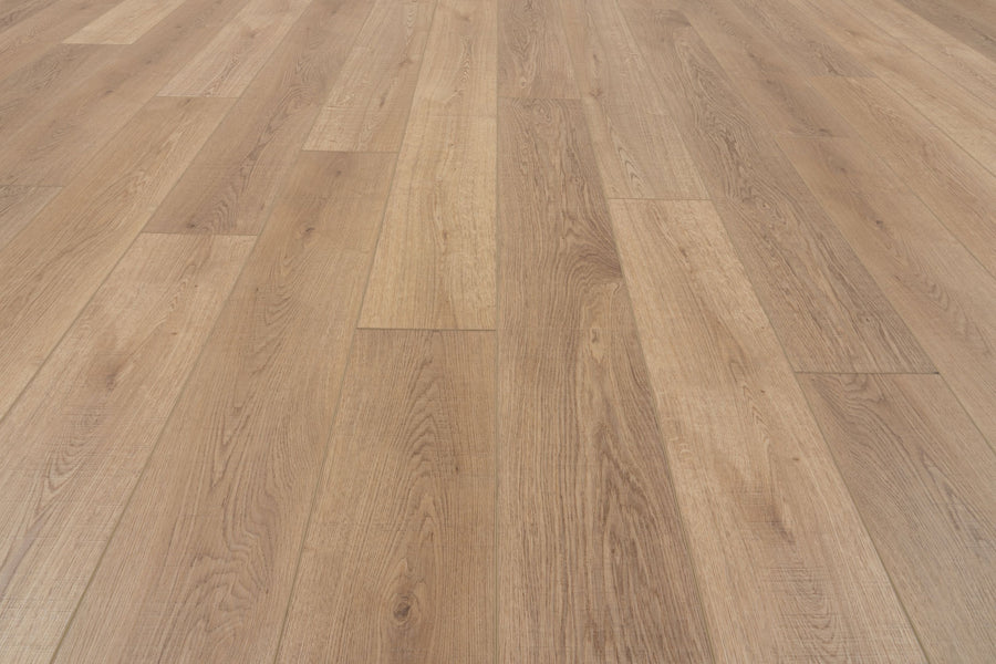 The Uptown Chic 7.15" Luxury Vinyl Plank features light brown wood tones with a natural grain pattern, arranged lengthwise for a clean, seamless look. The smooth surface appears even and well-maintained under bright lighting.