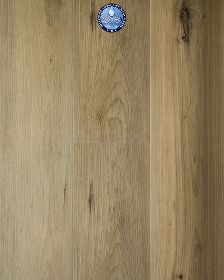 Natural-looking Uptown Chic 7.15" Luxury Vinyl Plank flooring with light wood grain and dark knots, plus a circular blue sticker with white text and graphic near the top center of the image.
