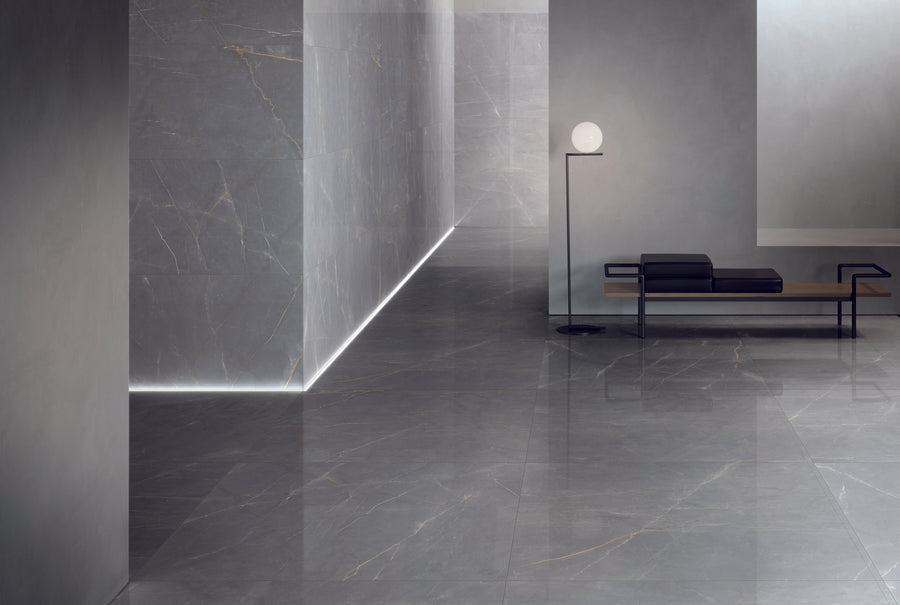 Minimalist interior with shiny gray marble floors and walls, a black and wood bench, a floor lamp with a round white light, and subtle wall strip lighting creating a modern, elegant atmosphere.