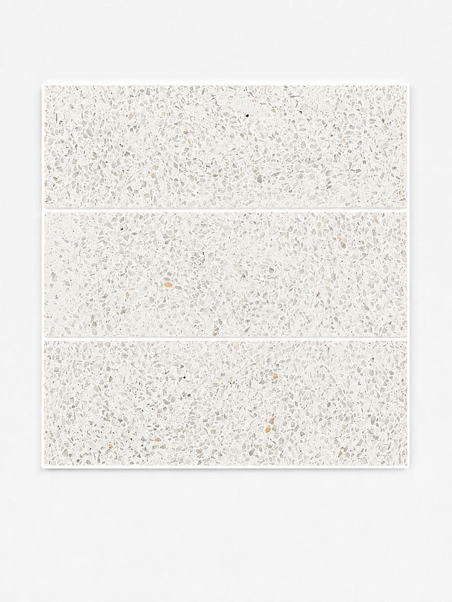 Three Revive Terazzo 4x12 Natural Stone tiles in the color Amplify, featuring a light gray and white speckled pattern reminiscent of elegant Dolomite Marble, are arranged in a vertical stack on a plain white background.