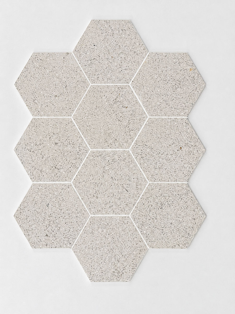 Nine Revive Korbell & Dolomite 5″ Hex Mosaic tiles in Amplify, a pale gray speckled color, are arranged in a honeycomb pattern on a white background.