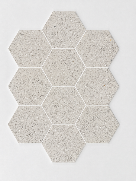 Nine Revive Korbell & Dolomite 5″ Hex Mosaic tiles in Amplify, a pale gray speckled color, are arranged in a honeycomb pattern on a white background.