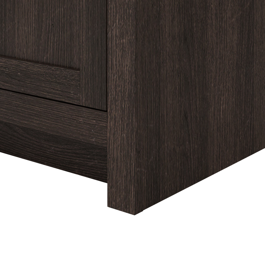 Close-up of the bottom corner of a dark wood cabinet or drawer unit, showing the texture and grain of the wood.