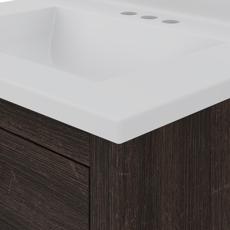 Close-up of a modern bathroom sink with a white rectangular basin and countertop, set atop a dark wood vanity with a horizontal drawer and three faucet holes visible in the countertop.