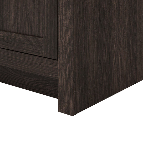 Close-up of the bottom corner of a dark wood cabinet or furniture piece, showing its texture, grain, and clean lines against a white background.