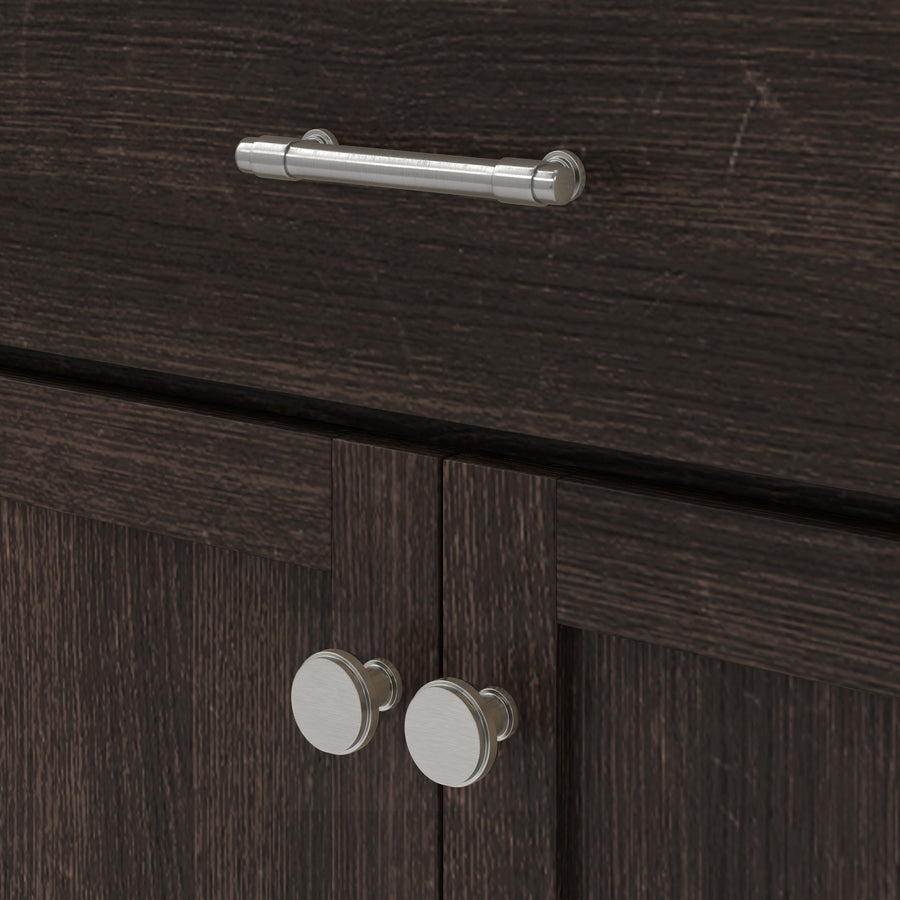 Close-up of a dark wood cabinet with two round silver knobs on the doors and a horizontal silver handle on the drawer above.