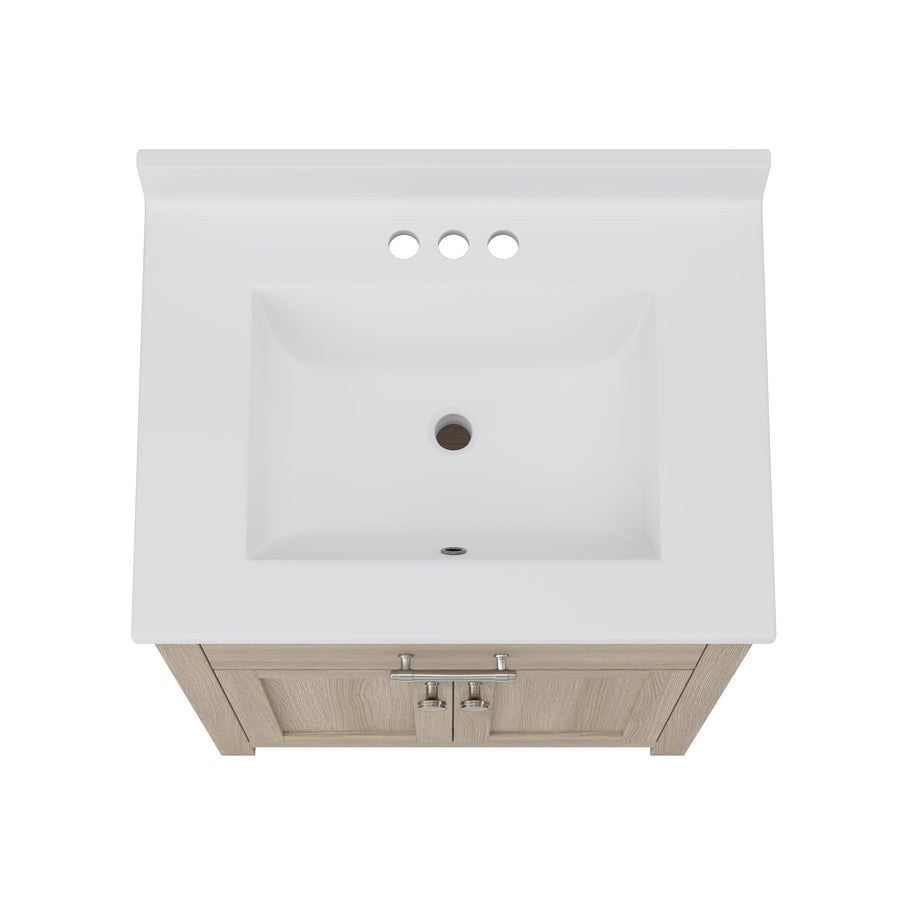 Overhead view of a white rectangular bathroom sink with three faucet holes, mounted on a light wood vanity cabinet with silver handles.