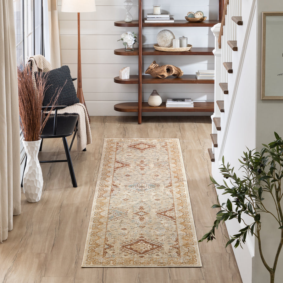 A hallway with light wood floors, a patterned runner rug, a black chair with cushions, a tall vase with dried branches, a wooden shelf with decor, and stairs with a white railing on the right.