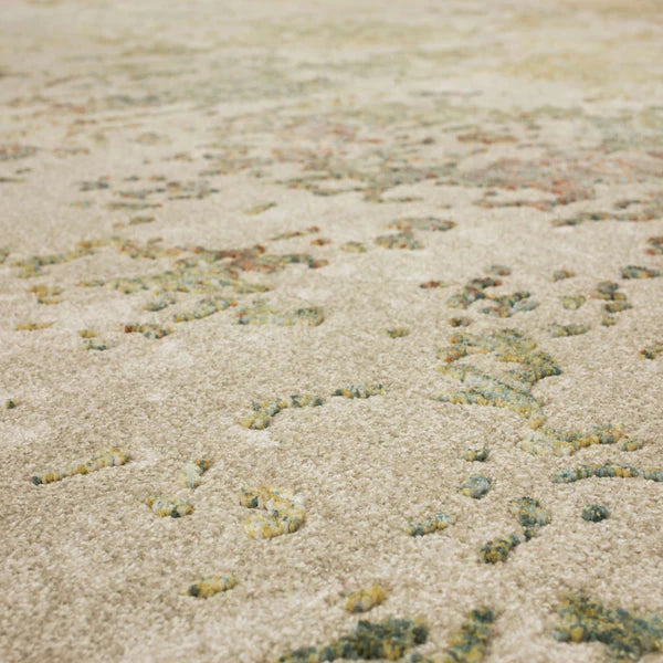 Close-up of a textured beige carpet with scattered green and yellow patterns, creating an abstract, mottled effect across the surface.