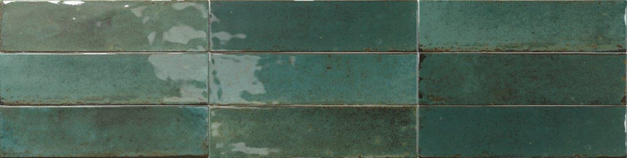 Two rows of Relic 2.7 x 11 Porcelain Tile in green, with a glossy finish and shade variation. Subtle reflections and dark grout lines highlight the handcrafted, rustic appeal.