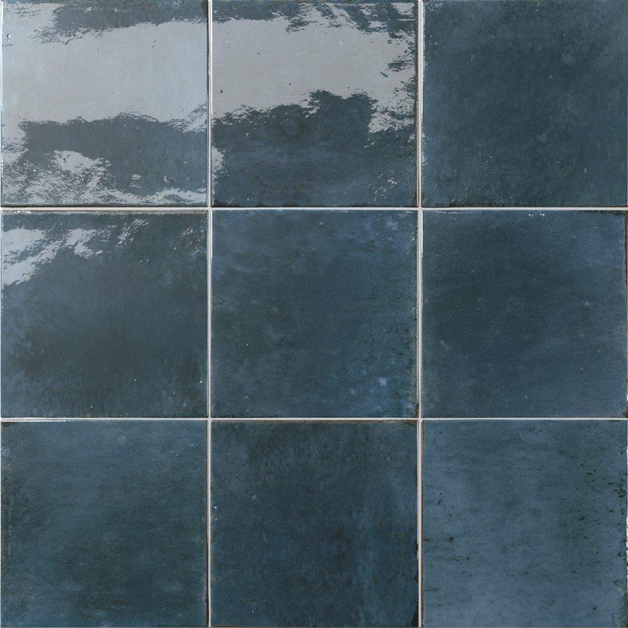 A close-up view of nine Relic 5.8 x 5.8 Porcelain Tiles in dark blue, arranged in a 3x3 grid, showcasing a glossy, reflective finish with subtle shade variation and textured surface.